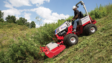 Ventrac slope mower with brush cutter mowing high weeds on impossibly steep hillside.